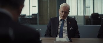 Movie still from “To Catch a Killer” (2023), directed by Damián Szifron – An older man sitting at a table in front of a laptop; Close Up shot, Over the shoulder angle