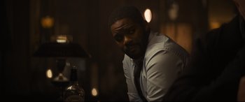 Movie still from “To Catch a Killer” (2023), directed by Damián Szifron – A man sitting at a table with a bottle of alcohol; Close Up shot, Over the shoulder angle