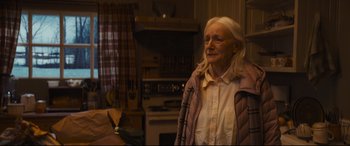 Movie still from “To Catch a Killer” (2023), directed by Damián Szifron – An older woman standing in a kitchen looking at the camera; Medium shot, Over the shoulder angle