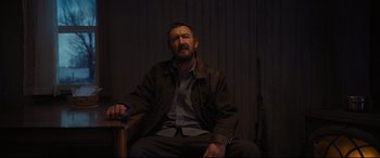 Movie still from “To Catch a Killer” (2023), directed by Damián Szifron – A man sitting in a chair in a dark room; Medium shot, Over the shoulder angle
