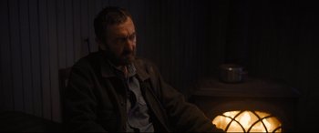 Movie still from “To Catch a Killer” (2023), directed by Damián Szifron – A man sitting in front of a candle in a dark room; Close Up shot, Over the shoulder angle