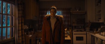 Movie still from “To Catch a Killer” (2023), directed by Damián Szifron – A woman standing in a kitchen wearing a jacket; Medium shot, Low angle
