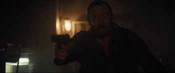 Movie still from “To Catch a Killer” (2023), directed by Damián Szifron – A man holding a gun in a dark room; Close Up shot, Over the shoulder angle