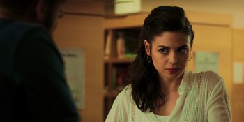 Movie still from “Dark Web: Cicada 3301” (2021), directed by Alan Ritchson – A woman with long dark brown hair wearing a white shirt; Close Up shot, Over the shoulder angle