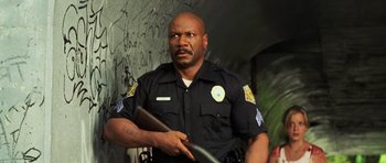 Movie still from “Dawn of the Dead” (2004), directed by Zack Snyder – A man in a police uniform holding a book; Medium shot, Low angle