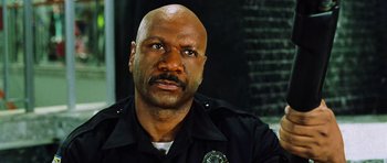 Movie still from “Dawn of the Dead” (2004), directed by Zack Snyder – A man in a police uniform looking at the camera; Close Up shot, Low angle
