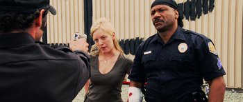 Movie still from “Dawn of the Dead” (2004), directed by Zack Snyder – A woman is being photographed by two police officers; Close Up shot, Over the shoulder angle