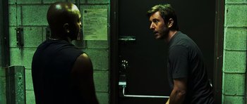 Movie still from “Dawn of the Dead” (2004), directed by Zack Snyder – A man standing next to another man near a door; Medium shot, Over the shoulder angle