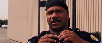 Movie still from “Dawn of the Dead” (2004), directed by Zack Snyder – A man in a police uniform putting on a watch; Close Up shot, High angle