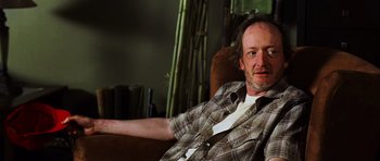 Movie still from “Dawn of the Dead” (2004), directed by Zack Snyder – A man sitting in a chair with his arm outstreched; Close Up shot, Low angle