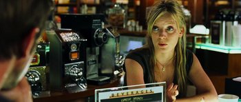 Movie still from “Dawn of the Dead” (2004), directed by Zack Snyder – A woman sitting at a counter in front of an espresso machine; Close Up shot, Over the shoulder angle