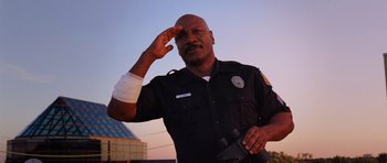 Movie still from “Dawn of the Dead” (2004), directed by Zack Snyder – A police officer saluting while holding his hand up; Medium shot, Low angle