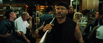 Movie still from “Dawn of the Dead” (2004), directed by Zack Snyder – A man in a black shirt and black hat holding a metal object; Close Up shot, Over the shoulder angle
