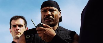 Movie still from “Dawn of the Dead” (2004), directed by Zack Snyder – A man holding a cell phone in his hand; Close Up shot, Low angle