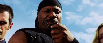 Movie still from “Dawn of the Dead” (2004), directed by Zack Snyder – A man with a black bandana on his head is talking on a cell phone; Close Up shot, Low angle