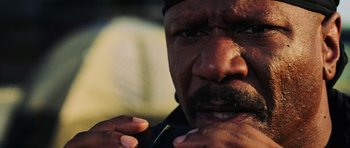 Movie still from “Dawn of the Dead” (2004), directed by Zack Snyder – A man with a beard and a black hat is holding his finger in his mouth; Close Up shot, Low angle