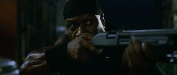 Movie still from “Dawn of the Dead” (2004), directed by Zack Snyder – A man with a black bandana on his head is holding a gun; Close Up shot, Low angle