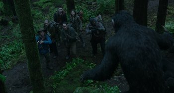 Movie still from “Dawn of the Planet of the Apes” (2014), directed by Matt Reeves – A group of people standing in the woods looking at a gorilla; Wide shot, Low angle