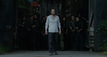 Movie still from “Dawn of the Planet of the Apes” (2014), directed by Matt Reeves – A man standing in front of a group of people; Medium shot, Over the shoulder angle