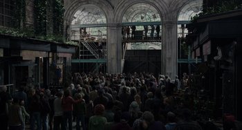 Movie still from “Dawn of the Planet of the Apes” (2014), directed by Matt Reeves – A crowd of people gathered in front of a building; Wide shot, Over the shoulder angle