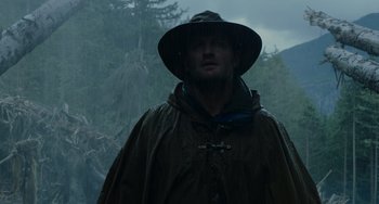 Movie still from “Dawn of the Planet of the Apes” (2014), directed by Matt Reeves – A man wearing a rain coat and a rain hat; Close Up shot, Low angle