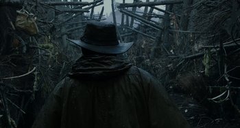 Movie still from “Dawn of the Planet of the Apes” (2014), directed by Matt Reeves – A man wearing a hat and a raincoat walking in the rain; Close Up shot, Over the shoulder angle