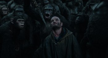 Movie still from “Dawn of the Planet of the Apes” (2014), directed by Matt Reeves – A man standing in front of a group of monkeys; Medium shot, Low angle
