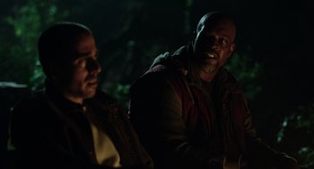 Movie still from “Dawn of the Planet of the Apes” (2014), directed by Matt Reeves – Two men are sitting in the dark in the woods; Close Up shot, Over the shoulder angle