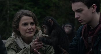 Movie still from “Dawn of the Planet of the Apes” (2014), directed by Matt Reeves – A woman holding a baby chimpanzee in her arms; Close Up shot, Over the shoulder angle