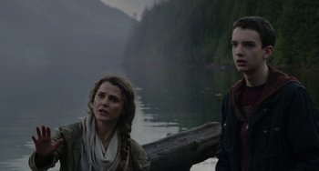 Movie still from “Dawn of the Planet of the Apes” (2014), directed by Matt Reeves – Two people standing next to each other near a body of water; Close Up shot, Over the shoulder angle