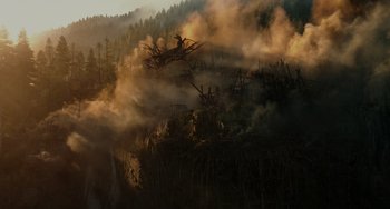 Movie still from “Dawn of the Planet of the Apes” (2014), directed by Matt Reeves – Smoke billows from a forest on top of a hill; Extreme Wide shot, High angle