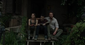 Movie still from “Dawn of the Planet of the Apes” (2014), directed by Matt Reeves – A man and two women sitting on a bench; Medium shot, High angle
