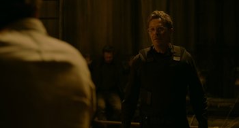 Movie still from “Dawn of the Planet of the Apes” (2014), directed by Matt Reeves – A man standing in front of a group of people; Medium shot, Over the shoulder angle