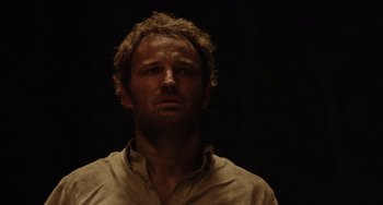 Movie still from “Dawn of the Planet of the Apes” (2014), directed by Matt Reeves – A person wearing a shirt and looking at the camera; Close Up shot, Low angle
