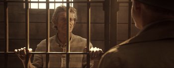 Movie still from “Dead for a Dollar” (2022), directed by Walter Hill – An older man in a jail cell looking through the bars; Medium shot, Over the shoulder angle