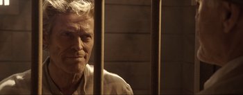 Movie still from “Dead for a Dollar” (2022), directed by Walter Hill – An old man sitting behind bars in a jail cell; Close Up shot, High angle
