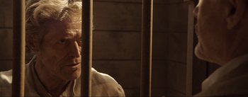 Movie still from “Dead for a Dollar” (2022), directed by Walter Hill – An older man sitting behind bars in a jail cell; Close Up shot, Low angle