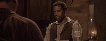 Movie still from “Dead for a Dollar” (2022), directed by Walter Hill – A man sitting at a table with a cup in front of him; Close Up shot, Over the shoulder angle