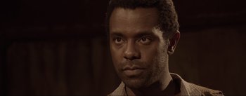 Movie still from “Dead for a Dollar” (2022), directed by Walter Hill – A black man with a beard is looking at the camera; Close Up shot, Over the shoulder angle