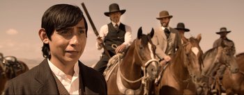 Movie still from “Dead for a Dollar” (2022), directed by Walter Hill – A man in a suit and a hat on a horse; Medium shot, Over the shoulder angle