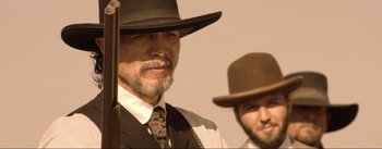 Movie still from “Dead for a Dollar” (2022), directed by Walter Hill – A man in a suit and a hat and a man with a beard; Close Up shot, Over the shoulder angle