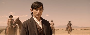 Movie still from “Dead for a Dollar” (2022), directed by Walter Hill – A man wearing a suit and tie standing next to a horse; Close Up shot, Over the shoulder angle