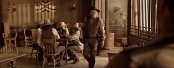 Movie still from “Dead for a Dollar” (2022), directed by Walter Hill – An old man walking in front of a group of people; Wide shot, Over the shoulder angle