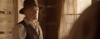 Movie still from “Dead for a Dollar” (2022), directed by Walter Hill – A man in a hat and a vest standing in a room; Close Up shot, Over the shoulder angle
