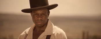 Movie still from “Dead for a Dollar” (2022), directed by Walter Hill – A man with a hat and a shirt on; Close Up shot, Over the shoulder angle