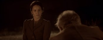 Movie still from “Dead for a Dollar” (2022), directed by Walter Hill – A young woman in a brown jacket looking at a man in a black suit; Medium shot, Over the shoulder angle