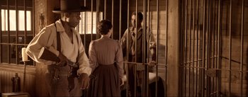 Movie still from “Dead for a Dollar” (2022), directed by Walter Hill – A group of people standing in front of a jail cell; Medium shot, Over the shoulder angle