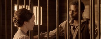 Movie still from “Dead for a Dollar” (2022), directed by Walter Hill – A man and a woman sitting in front of a jail cell; Medium shot, Over the shoulder angle