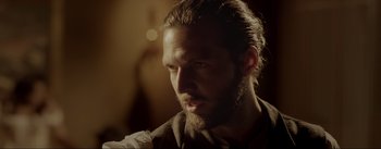 Movie still from “Dead for a Dollar” (2022), directed by Walter Hill – A man with long hair and a goatee is looking at the camera; Close Up shot, Over the shoulder angle