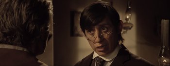 Movie still from “Dead for a Dollar” (2022), directed by Walter Hill – A man wearing glasses and a suit and tie; Close Up shot, Over the shoulder angle